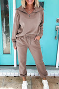 Woman wearing beige Goat Zip Collar long sleeve top and drawstring pants set with white sneakers standing by turquoise door