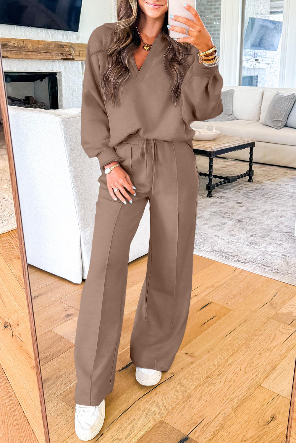 Woman wearing dark khaki polo collar V-neck pullover and drawstring sweatpants set with white sneakers indoors